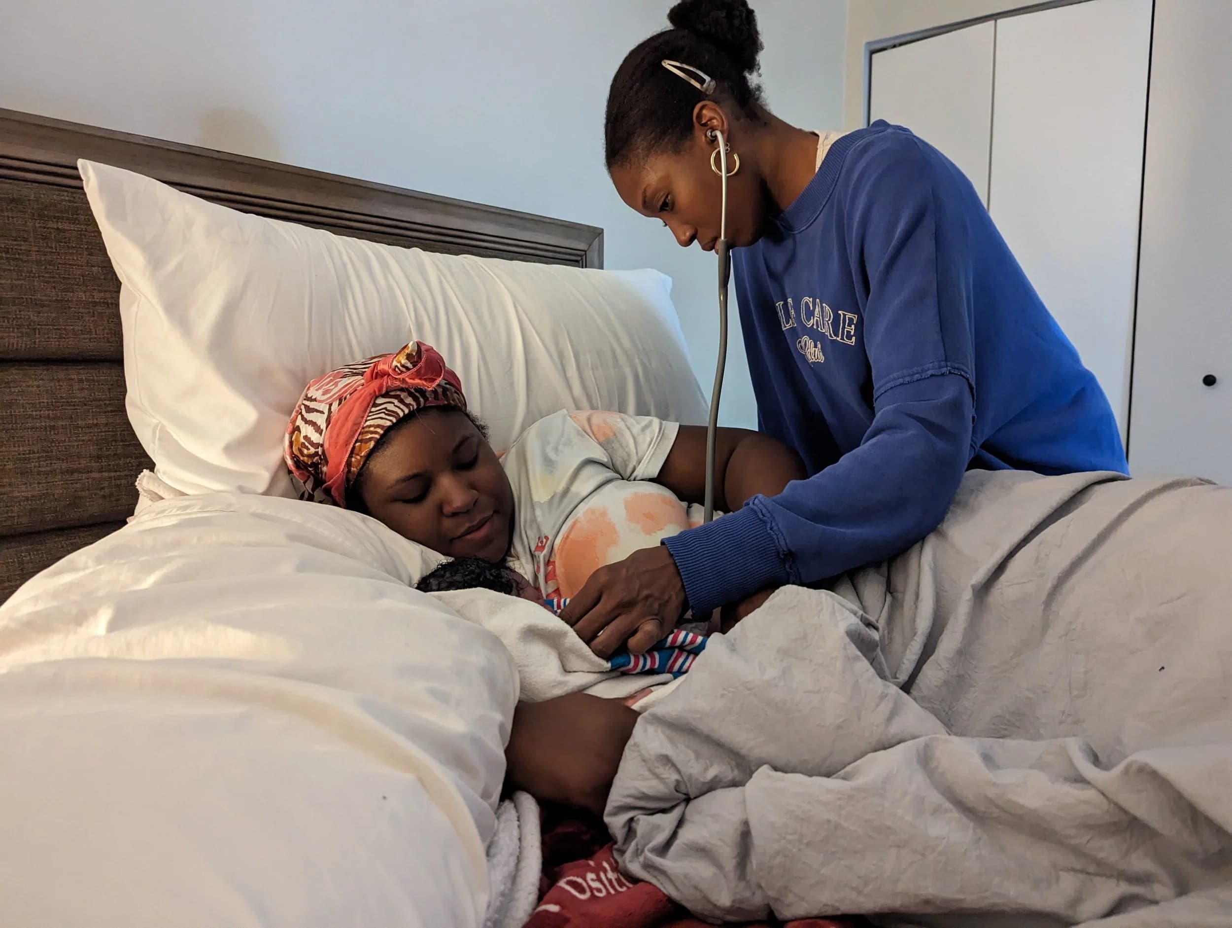 Abiana listening with a stethoscope during a home visit